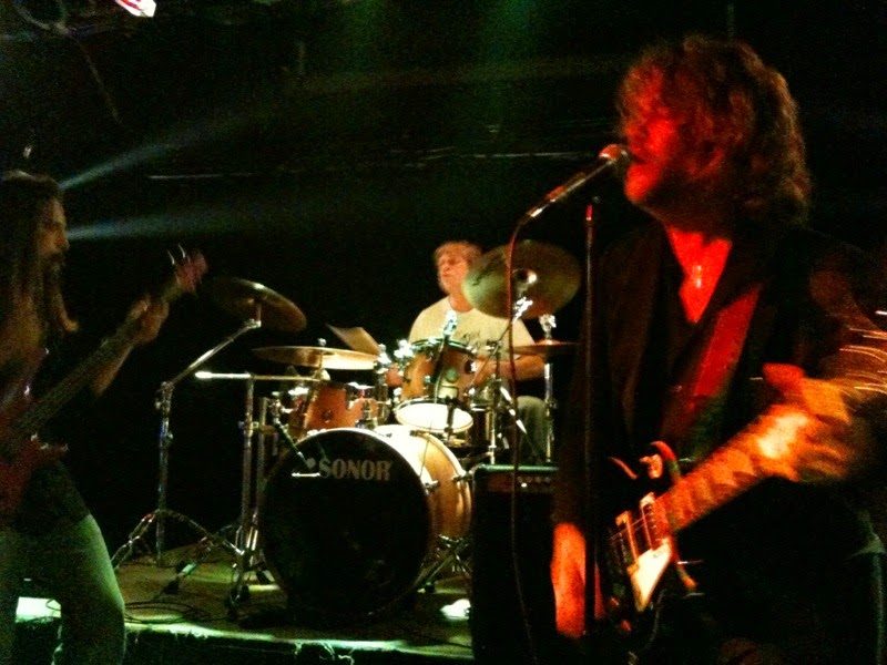 V singing and playing guitar with a full band