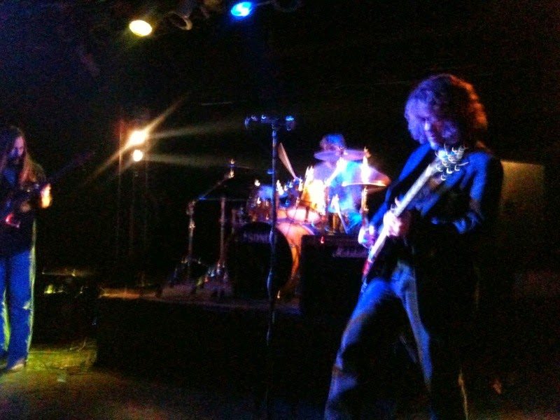 V on electric guitar with his band under stage lights